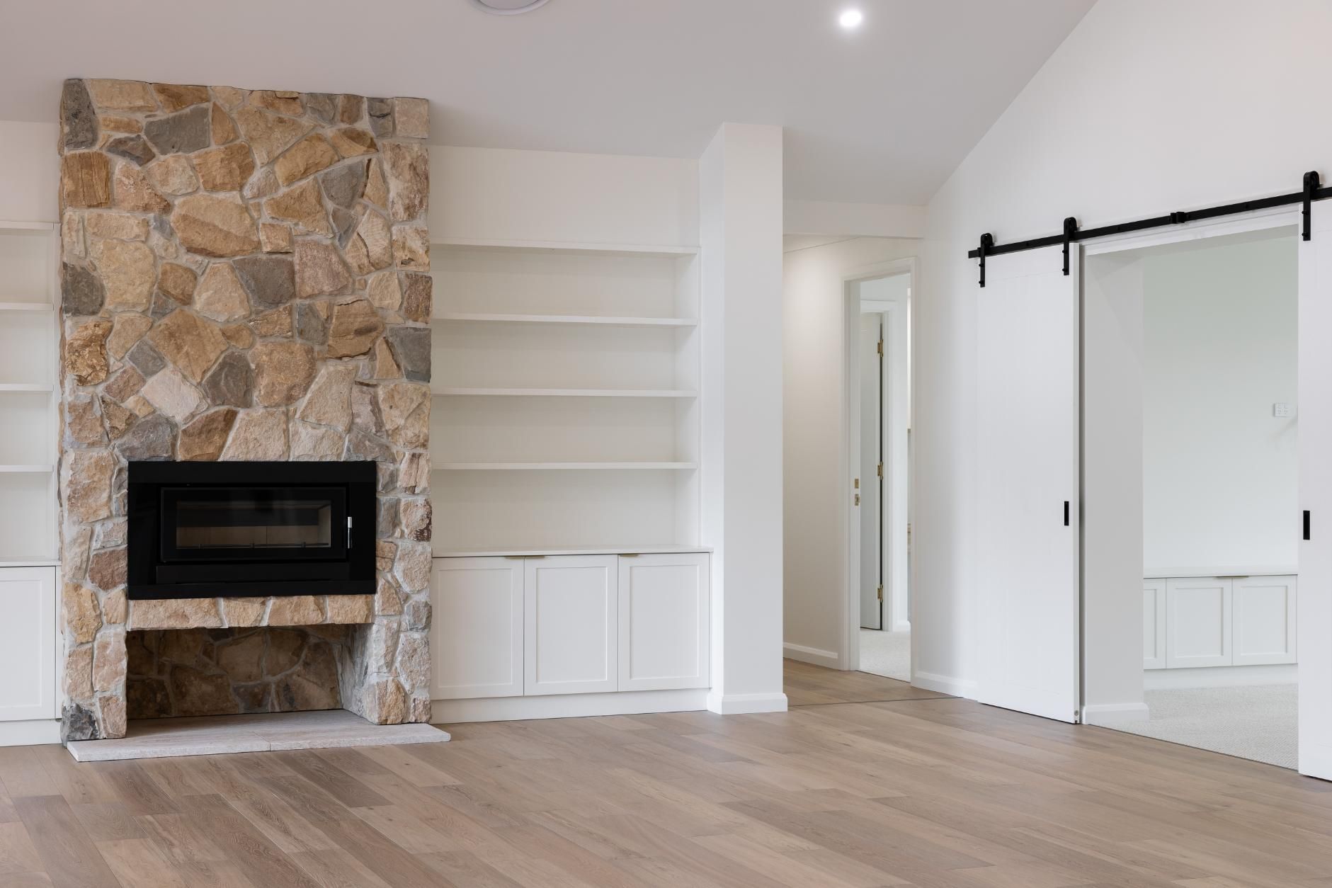 An Empty Living Room With Sliding Barn Doors — Windamere Homes in Highfields, QLD