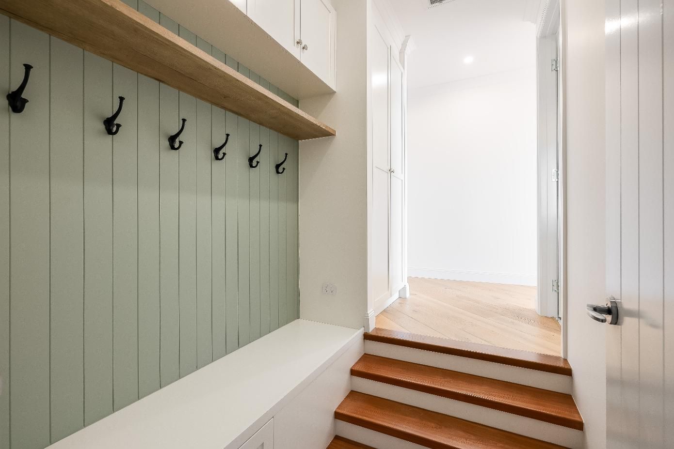 A Hallway With Stairs and Hooks on the Wall — Windamere Homes in Highfields, QLD