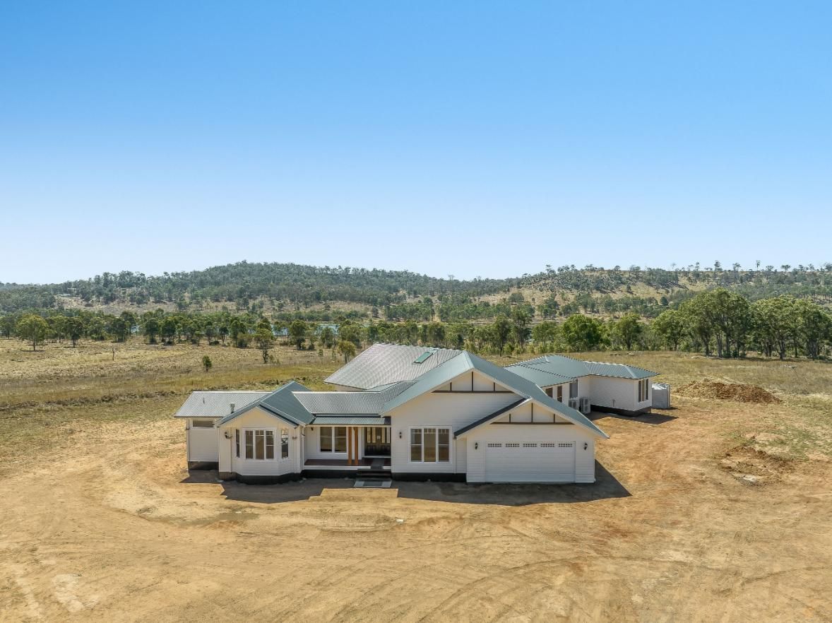 A Large White House is Sitting in the Middle of a Dirt Field — Windamere Homes in Highfields, QLD