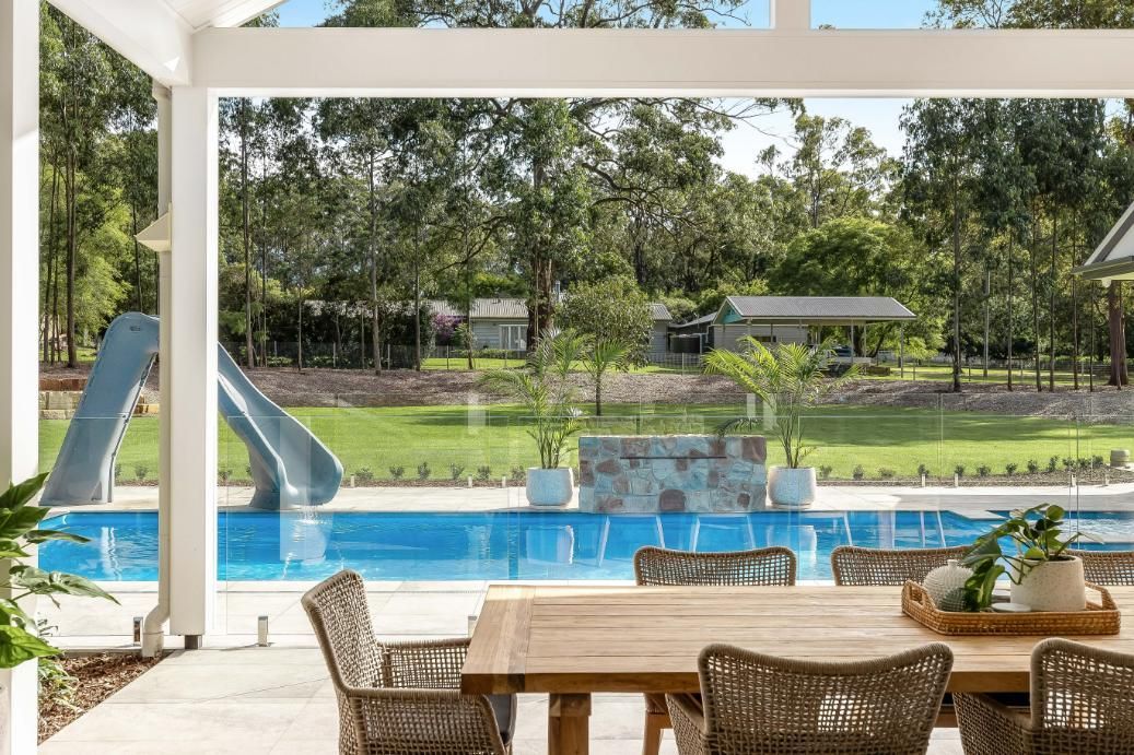 A Patio With a Table and Chairs and a View of a Swimming Pool — Windamere Homes in Highfields, QLD