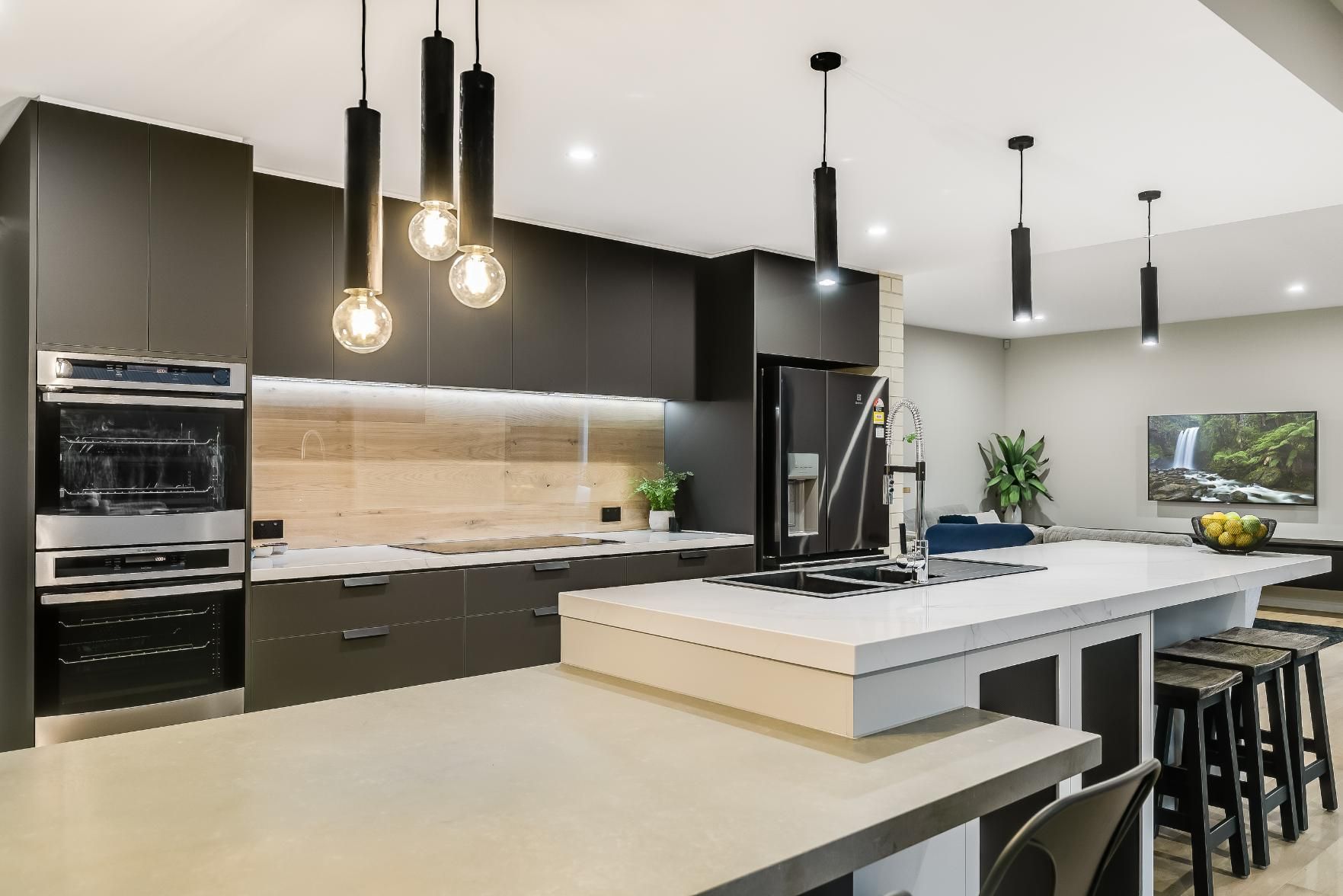 A Kitchen With a Large Island , Stools and a Refrigerator — Windamere Homes in Highfields, QLD