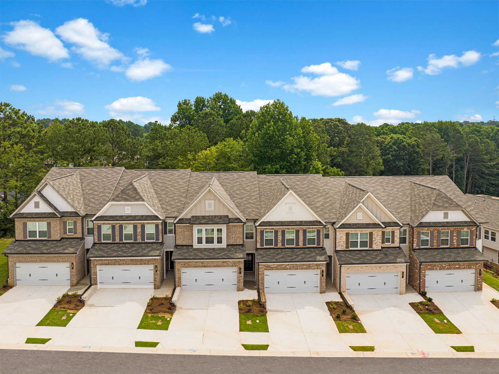 An aerial view of a row of houses with garages and trees in the background at Collins Place.