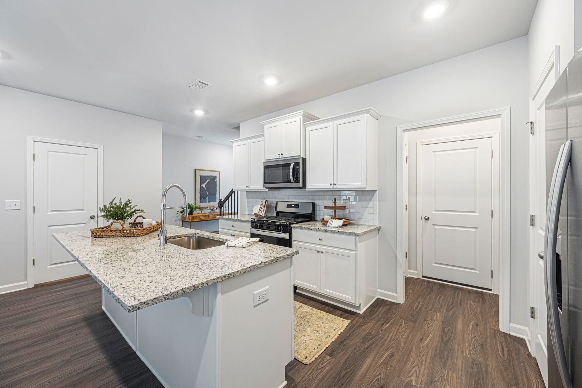 A kitchen with white cabinets , granite counter tops , a stove , microwave and refrigerator at Collins Place.