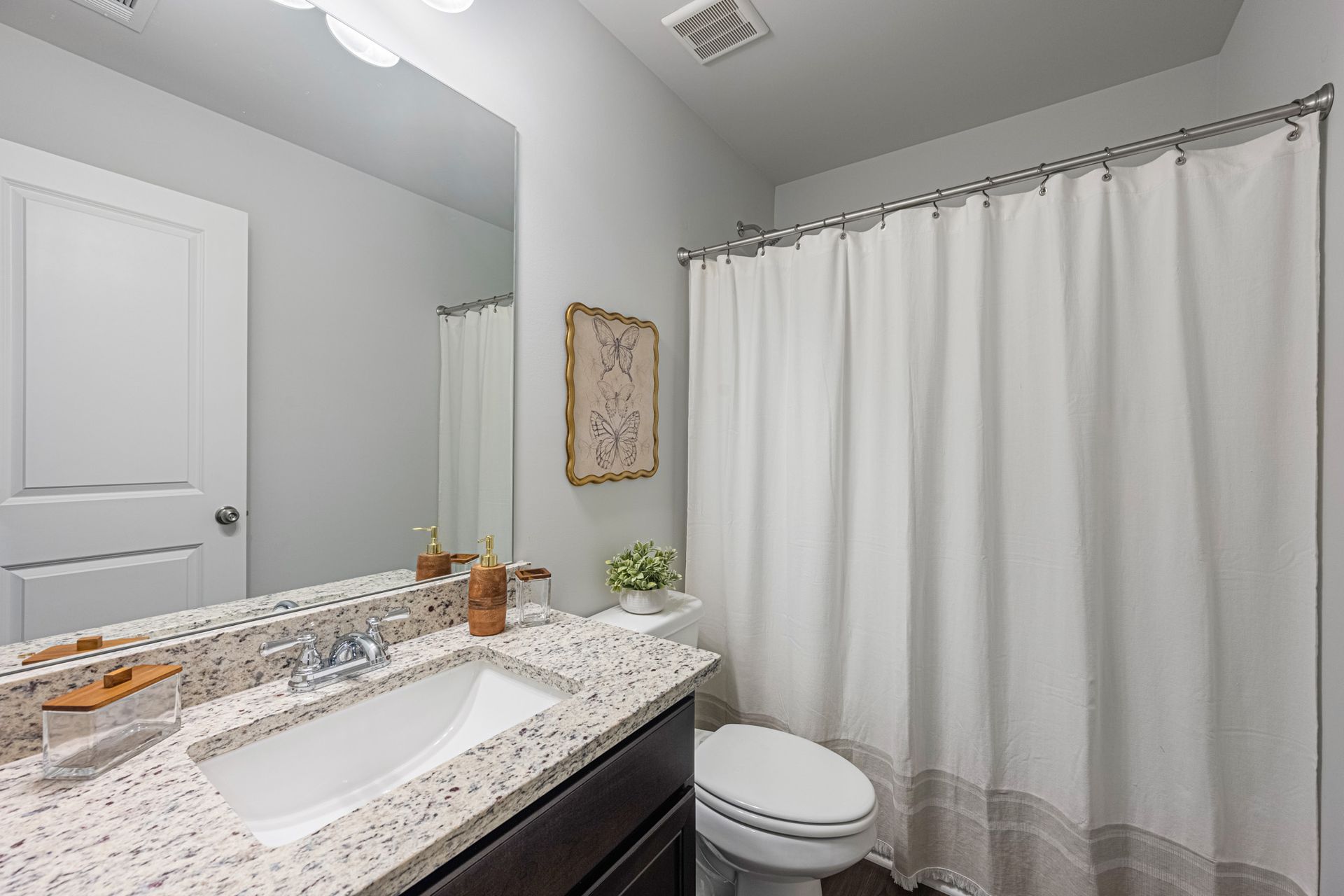 A bathroom with a sink , toilet , shower curtain and mirror at Collins Place.