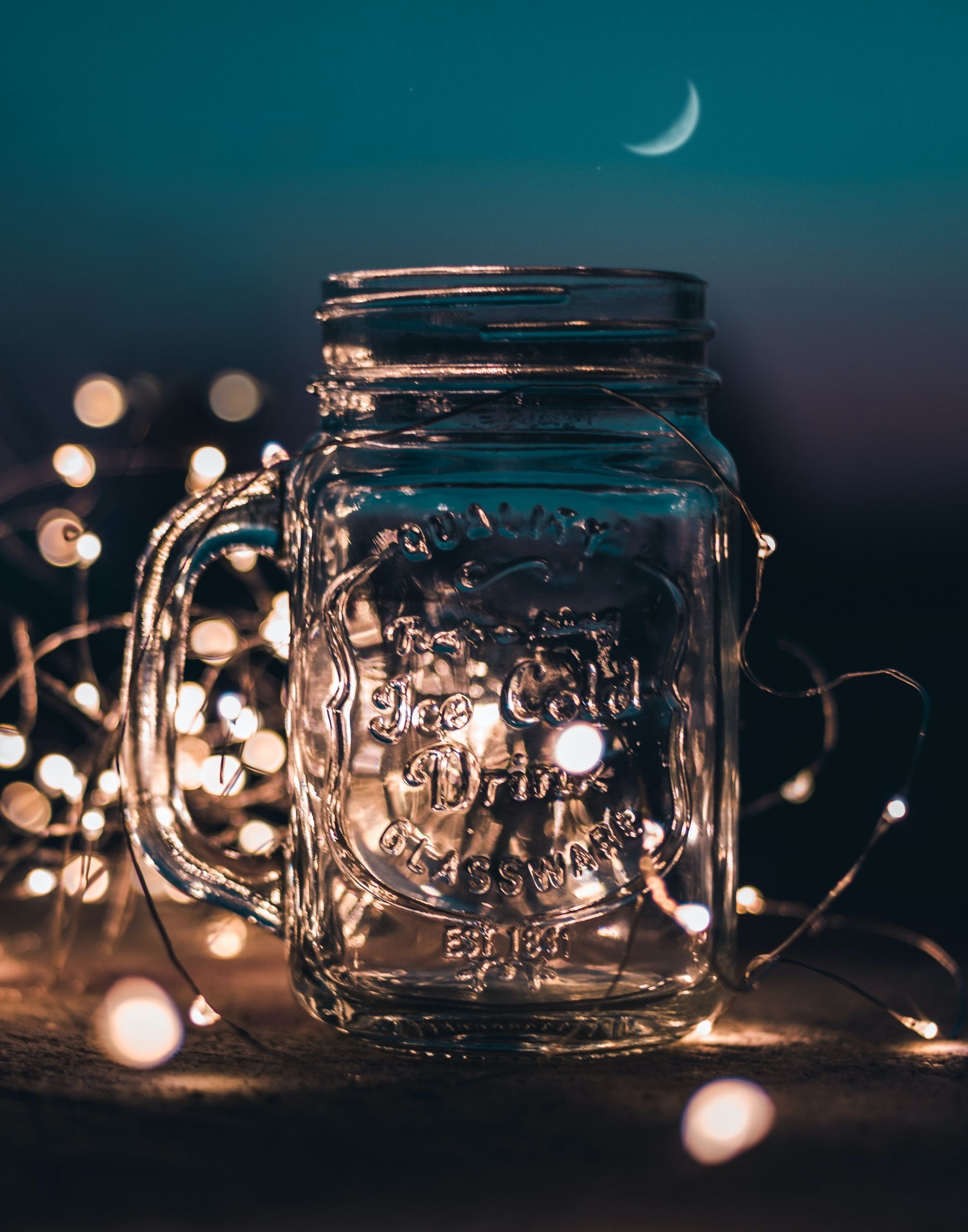 A mason jar is sitting on a table next to a string of lights.