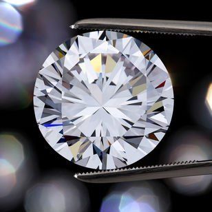 A close up of a diamond in tweezers on a black background