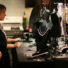 A woman is standing in front of a table full of jewelry.
