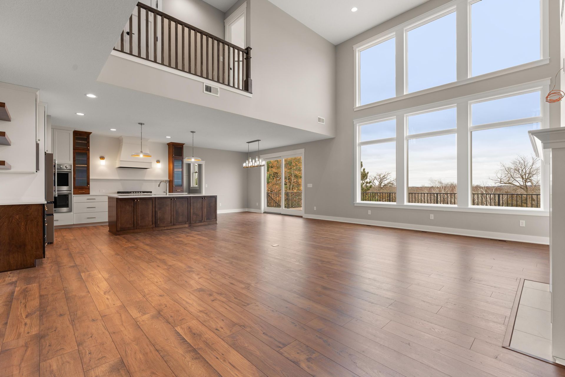 Spacious, open-concept living space with hardwood floors, kitchen, and large windows overlooking a scenic view.