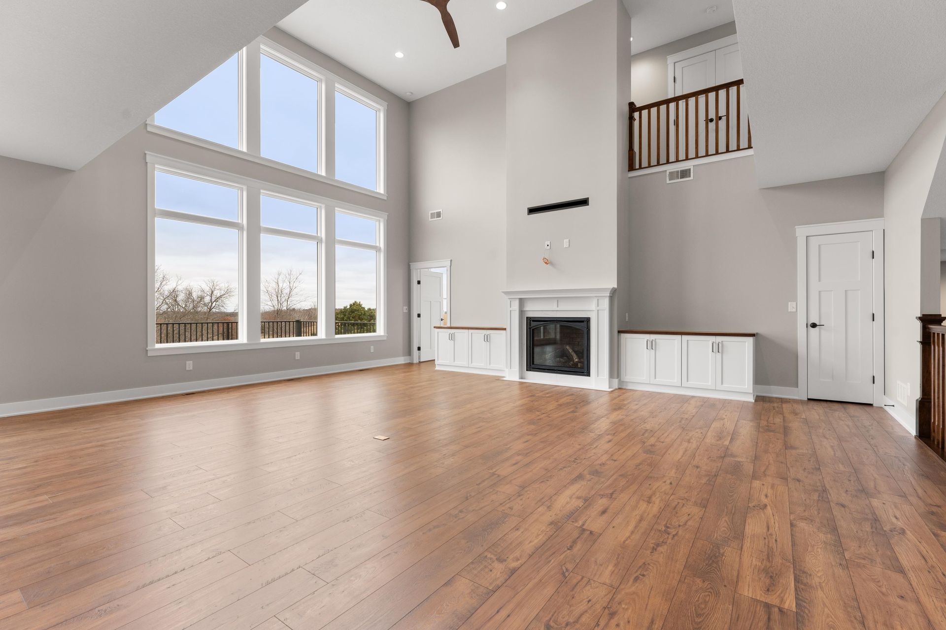 Spacious living room with high ceilings, large windows, fireplace, and hardwood floors.