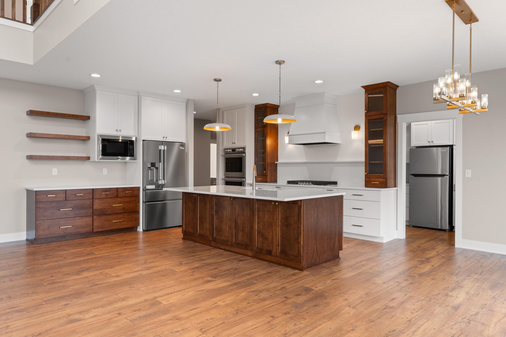 Modern kitchen with brown island, white cabinets, stainless steel appliances, and hardwood floors.
