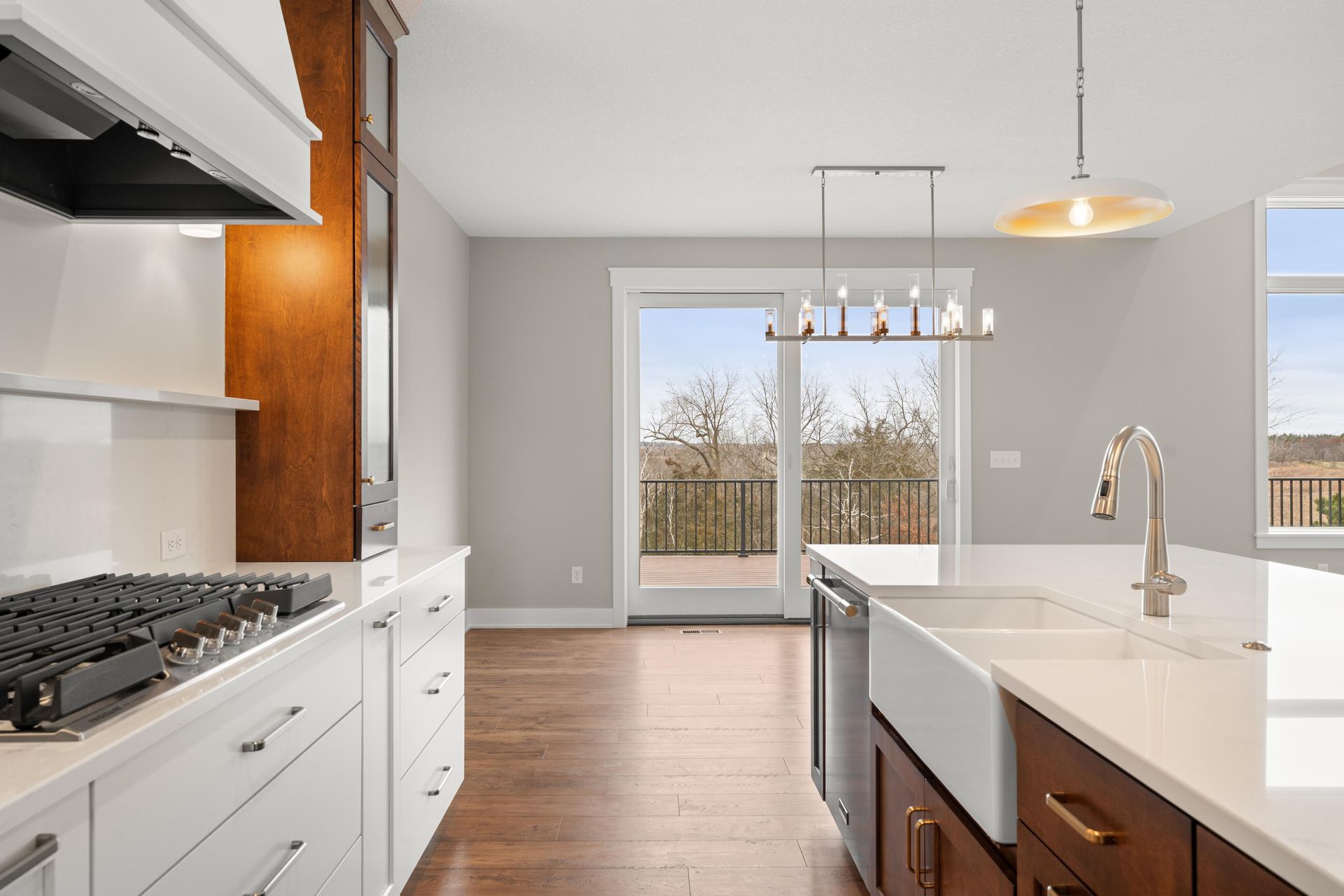 Modern kitchen with white cabinets, stainless steel appliances, and a view of a wooded area.