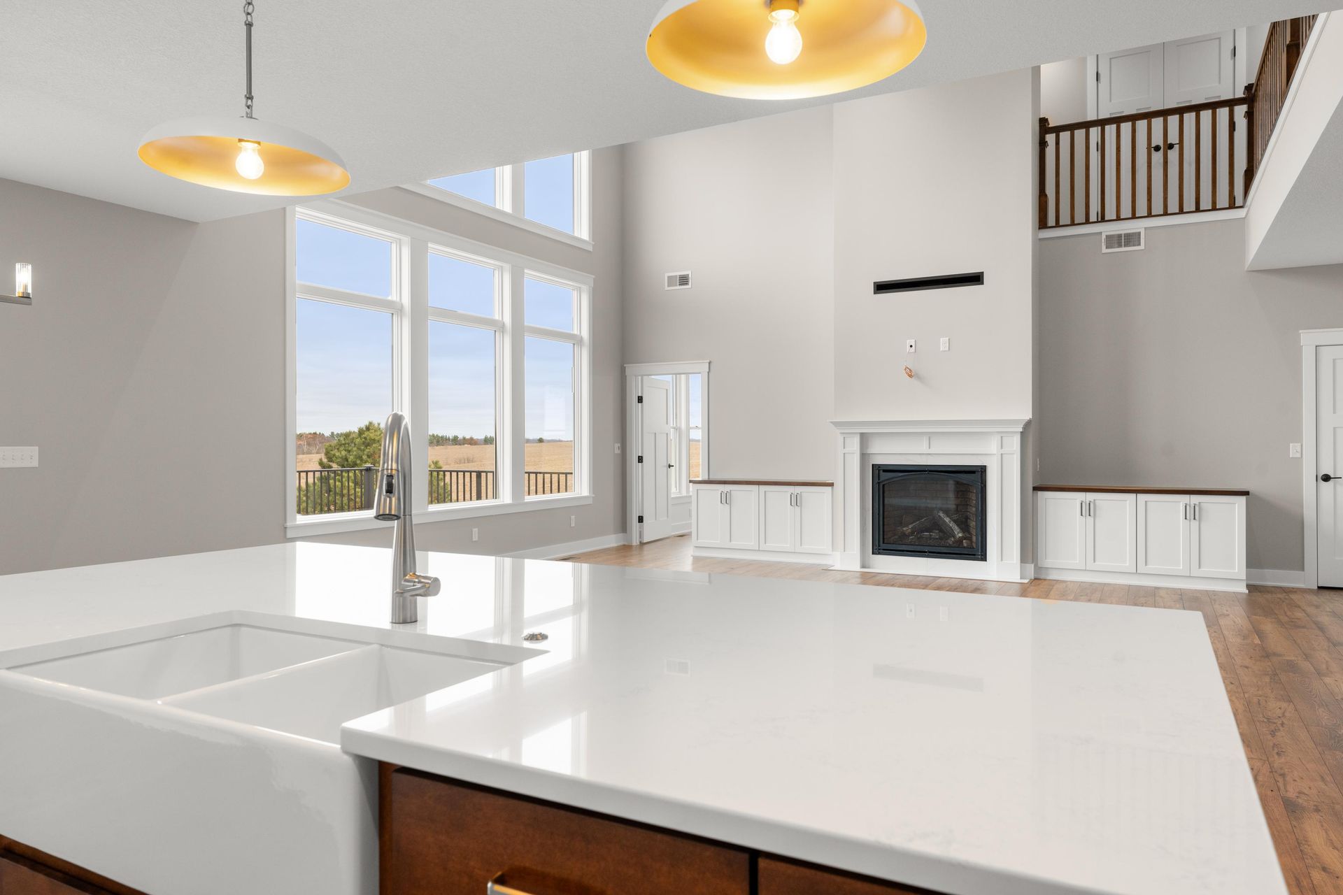 Open-concept kitchen and living room with white counters, fireplace, and large windows.
