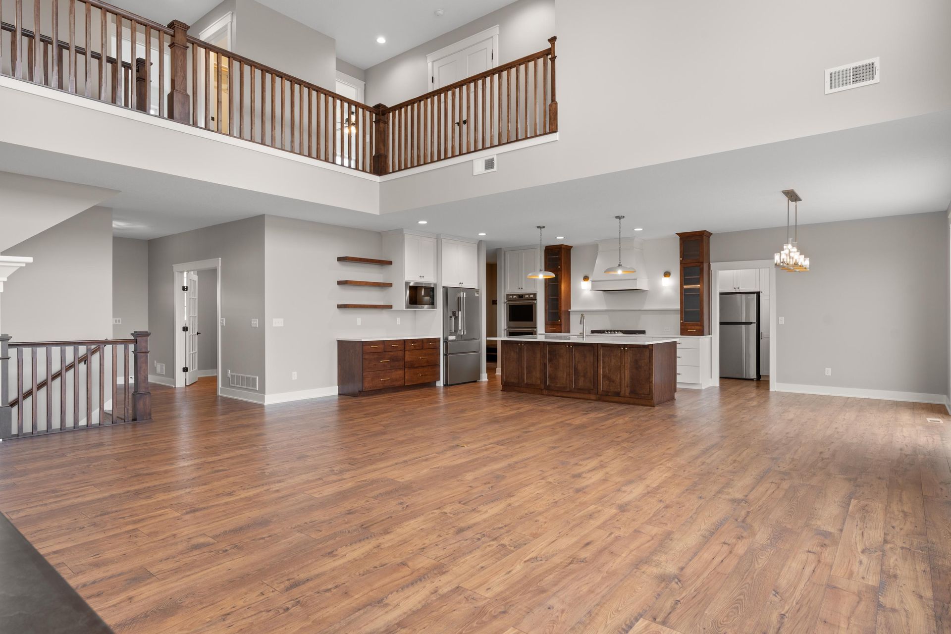 Spacious, light-filled open-concept living area with hardwood floors, kitchen, and a second-story loft.