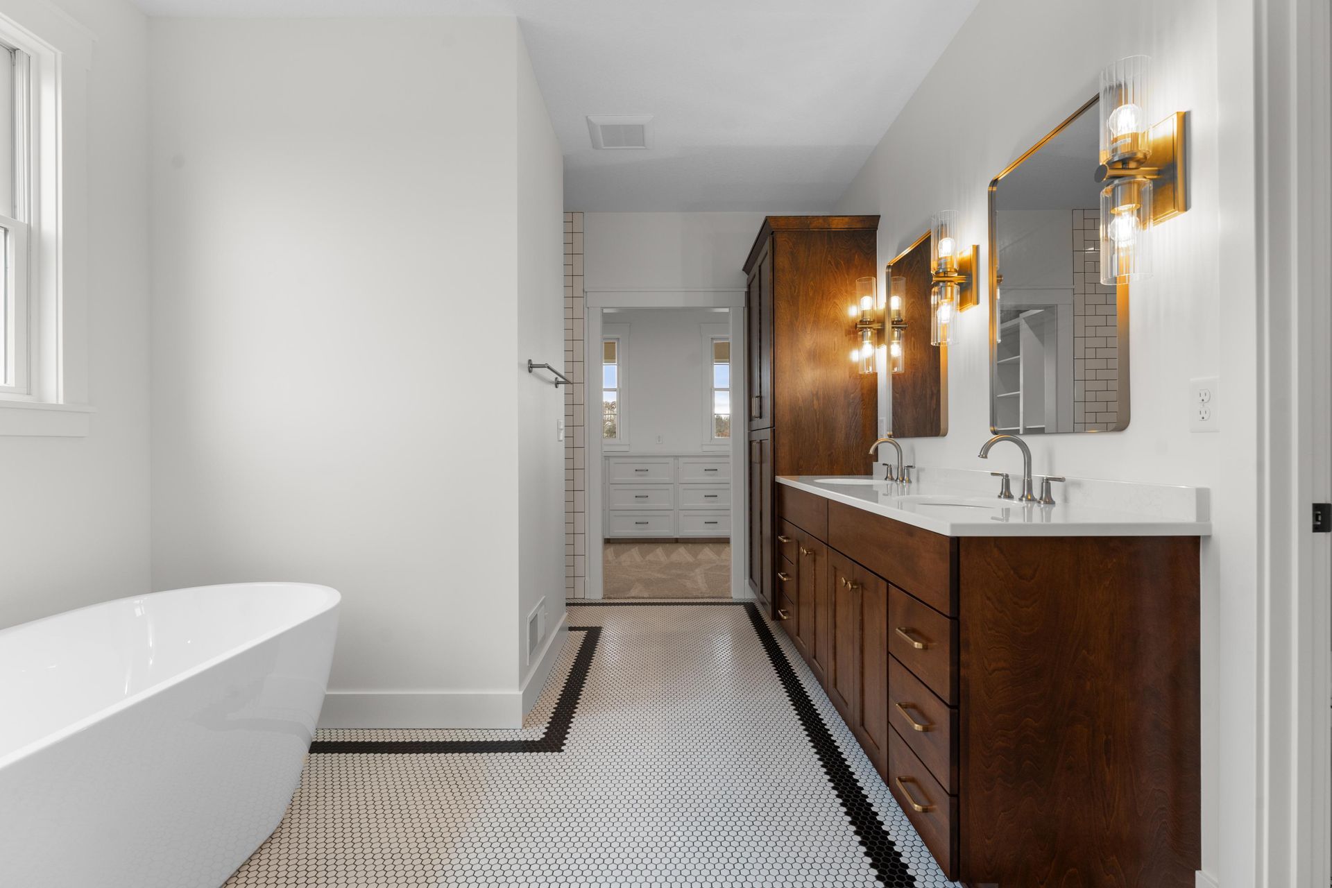 Modern bathroom with freestanding tub, vanity, dark wood cabinetry, and patterned tile floor.