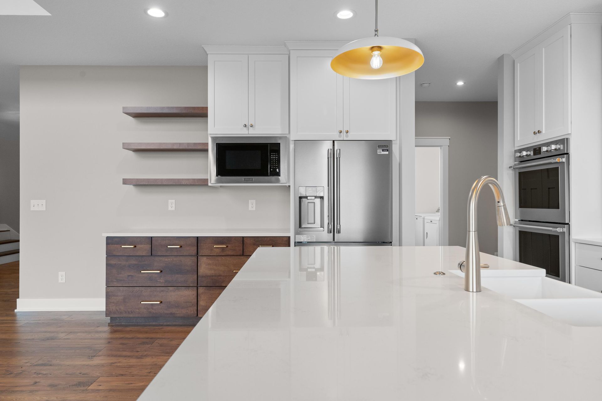 Modern kitchen with white cabinets, stainless steel appliances, and large island with sink.