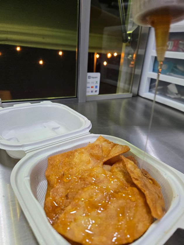 Two burritos with ground filling, grapes, tomatoes, wrapped in foil, on a colorful plate.