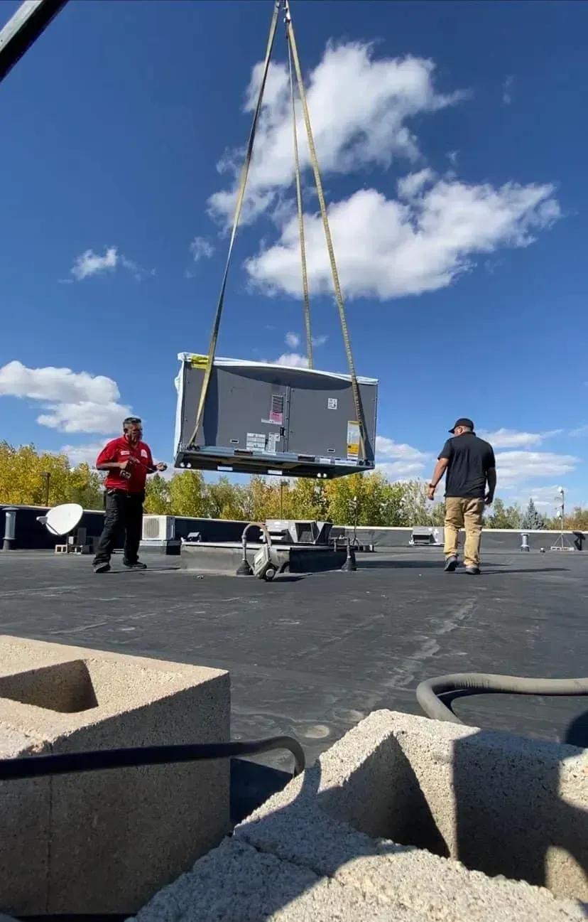A crane is lifting a box on top of a roof