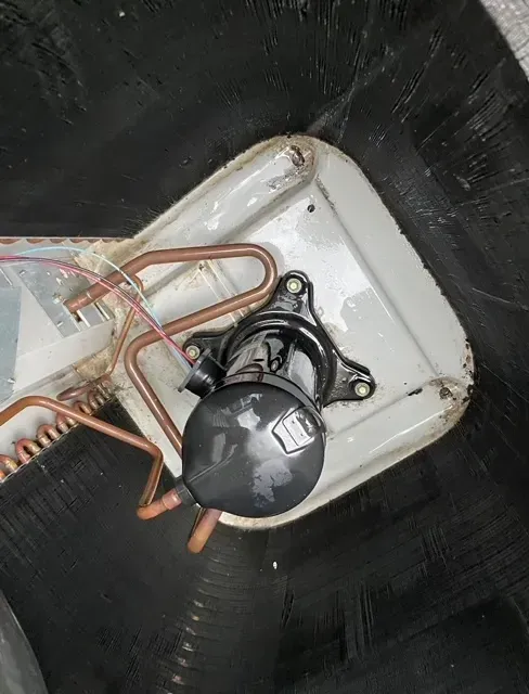 A close up of a compressor with copper pipes attached to it.