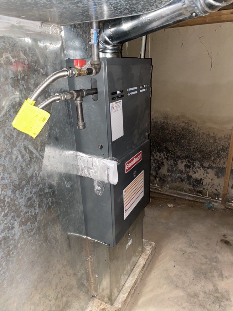A gas heater is sitting in a basement next to a wall.