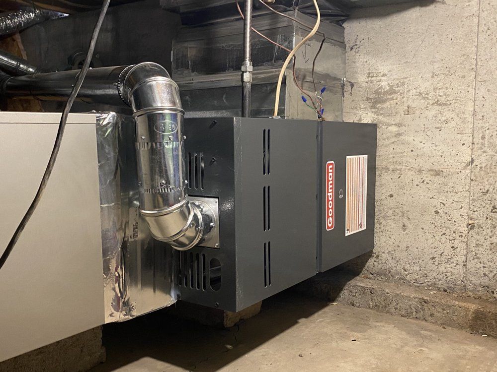 A furnace is sitting in a basement next to a wall.