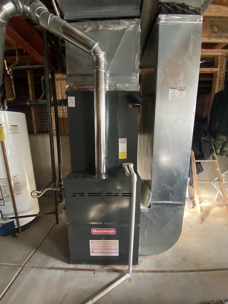 A furnace is sitting in a basement next to a water heater.