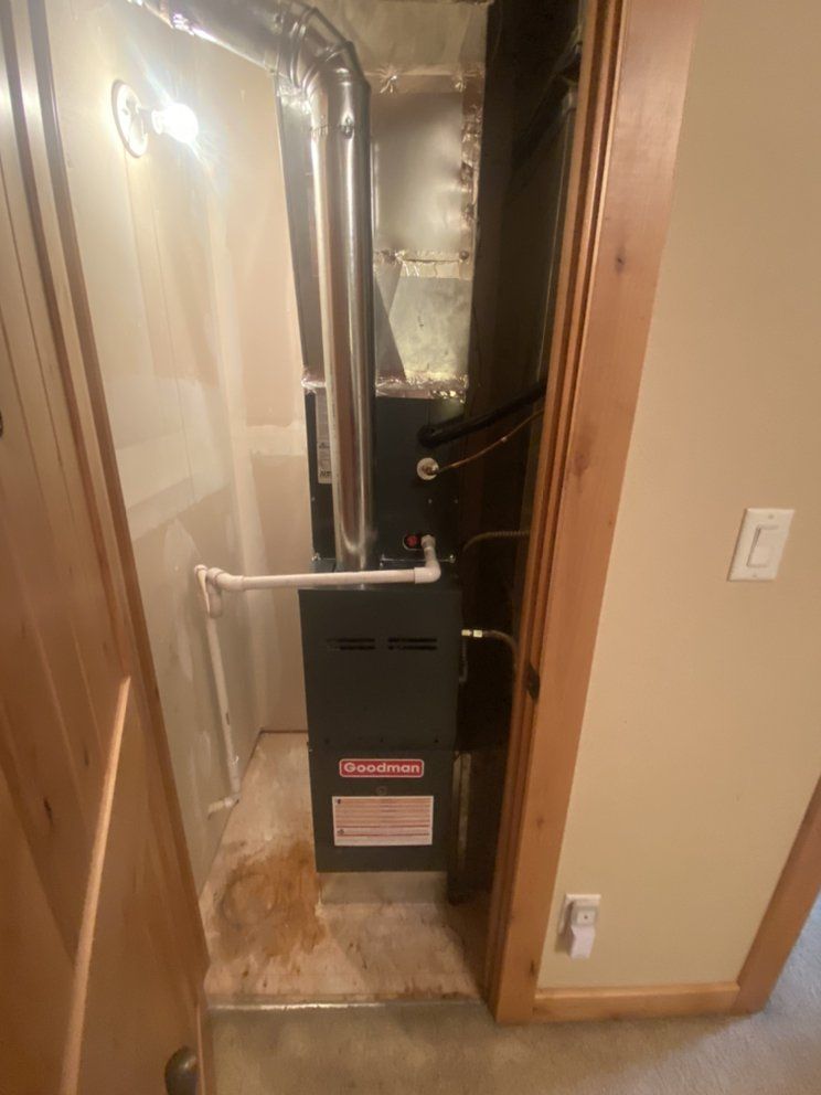 A furnace is sitting in the corner of a room next to a door.