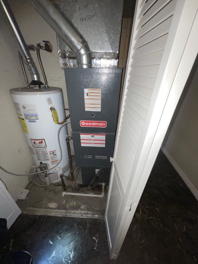 A water heater is sitting next to a furnace in a room.