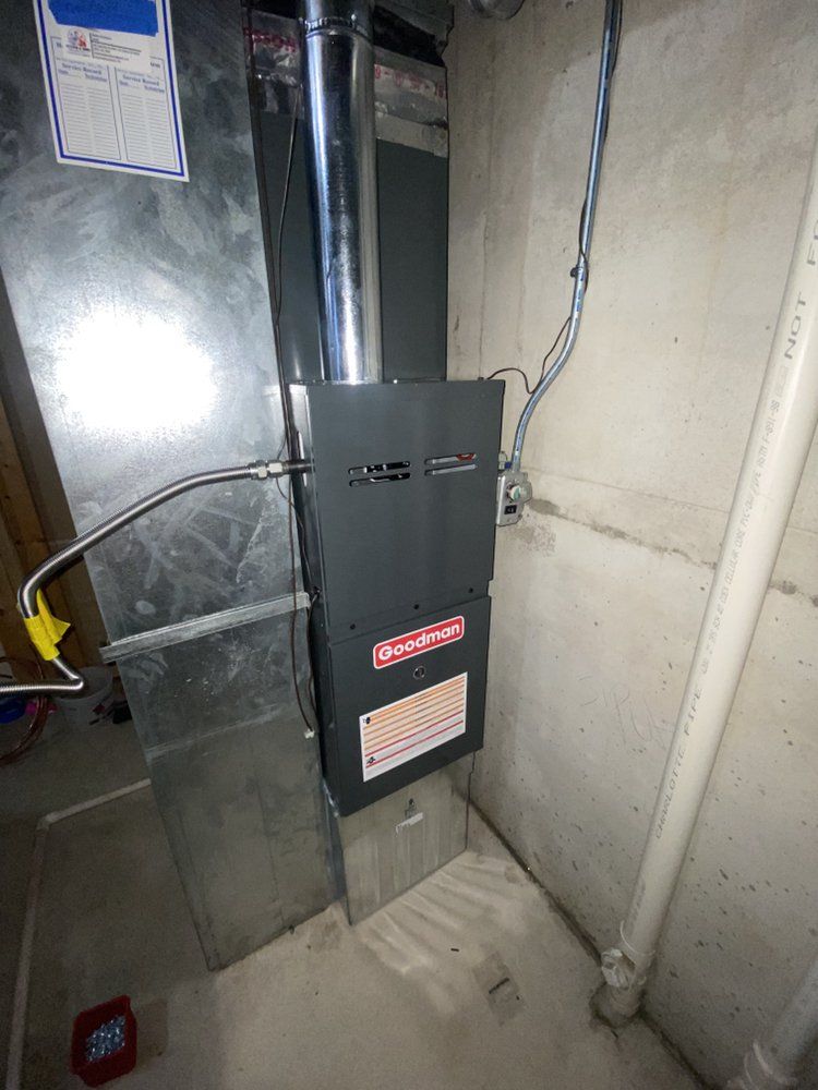 A furnace is sitting in a basement next to a wall.