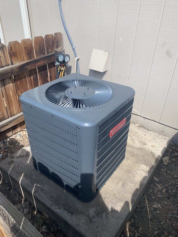 A large air conditioner is sitting on top of a concrete block.
