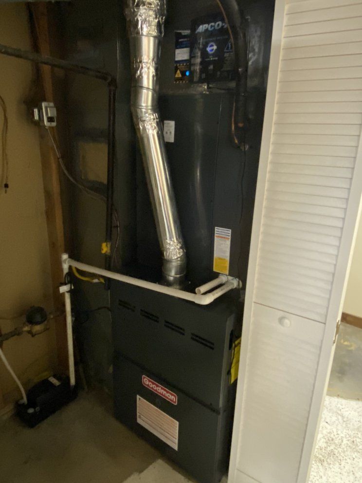 A black heater is sitting in a room next to a white cabinet.