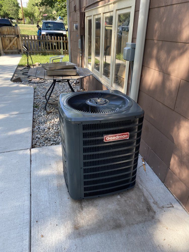 An air conditioner is sitting on the sidewalk next to a house.