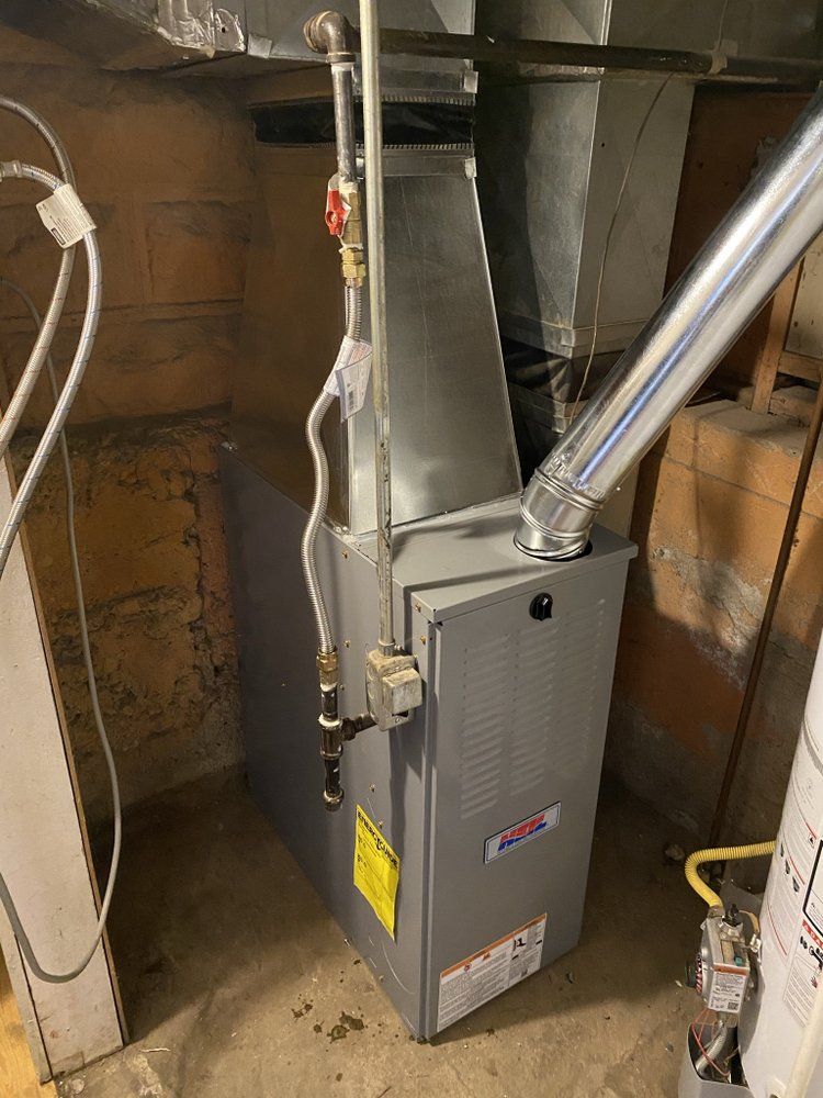 A furnace is sitting in a basement next to a water heater.