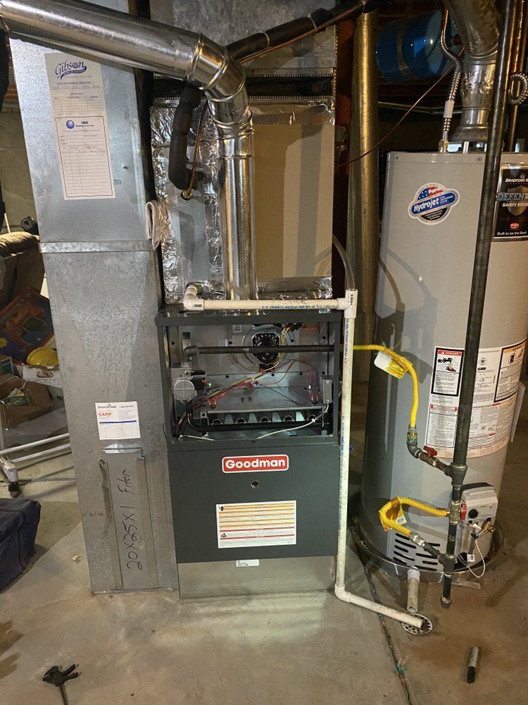 A gas heater is sitting next to a water heater in a basement.