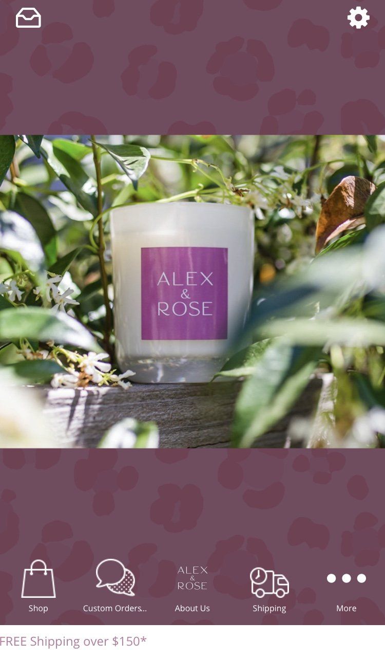 A white candle with a purple label is sitting on a wooden table.