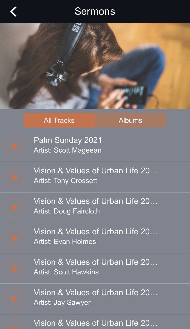 A woman wearing headphones is looking at her phone.