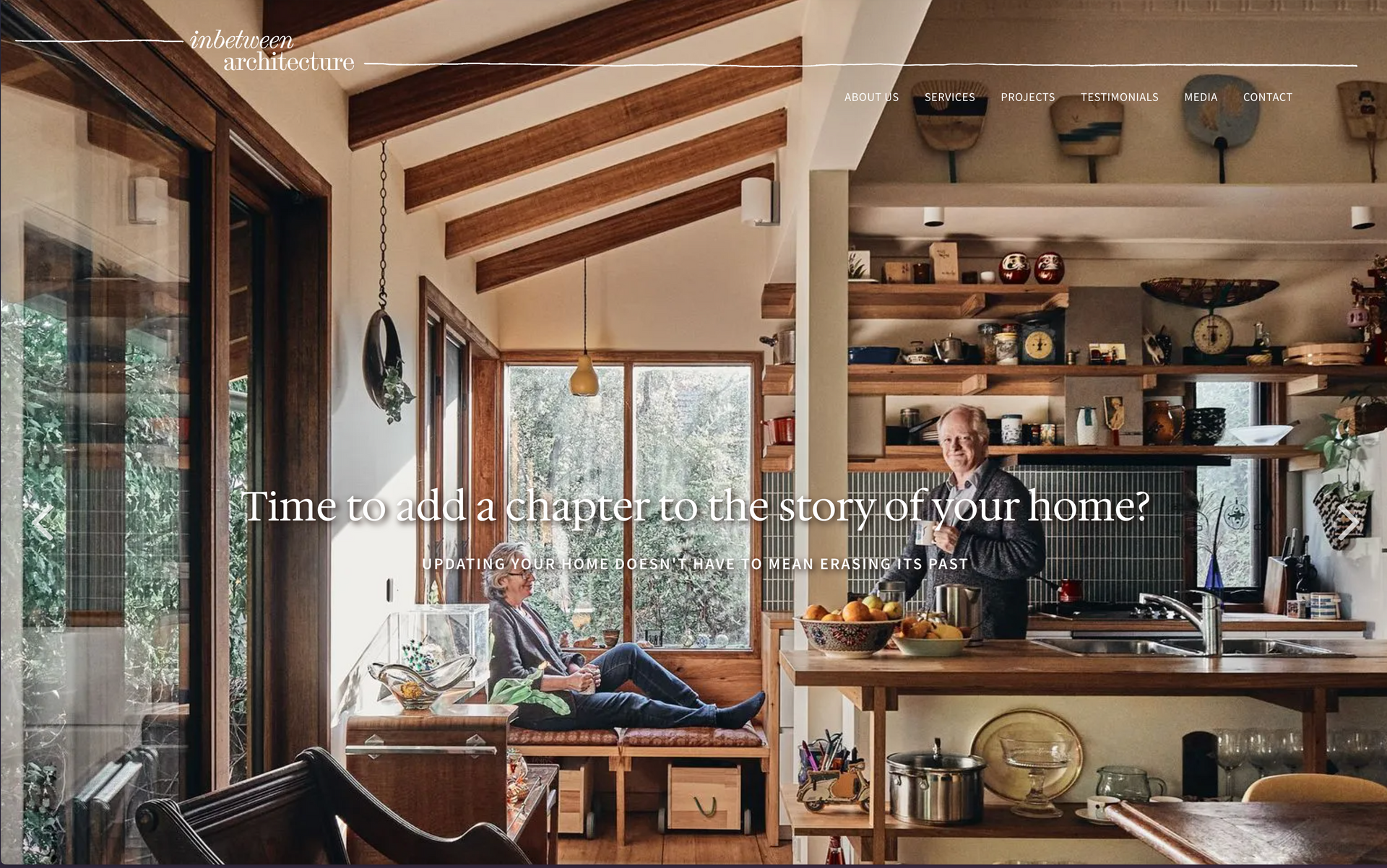 A man is sitting on a couch in a living room next to a kitchen. inbetween architecture website