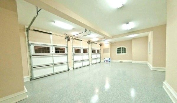 A large empty garage with white garage doors and a window.