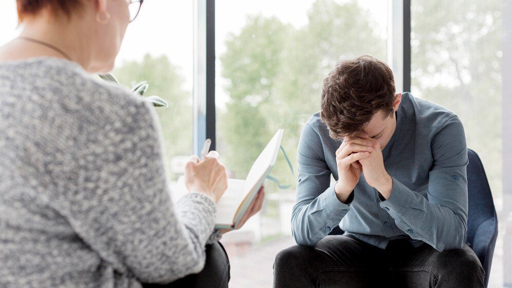 A man is sitting in a chair talking to a woman.