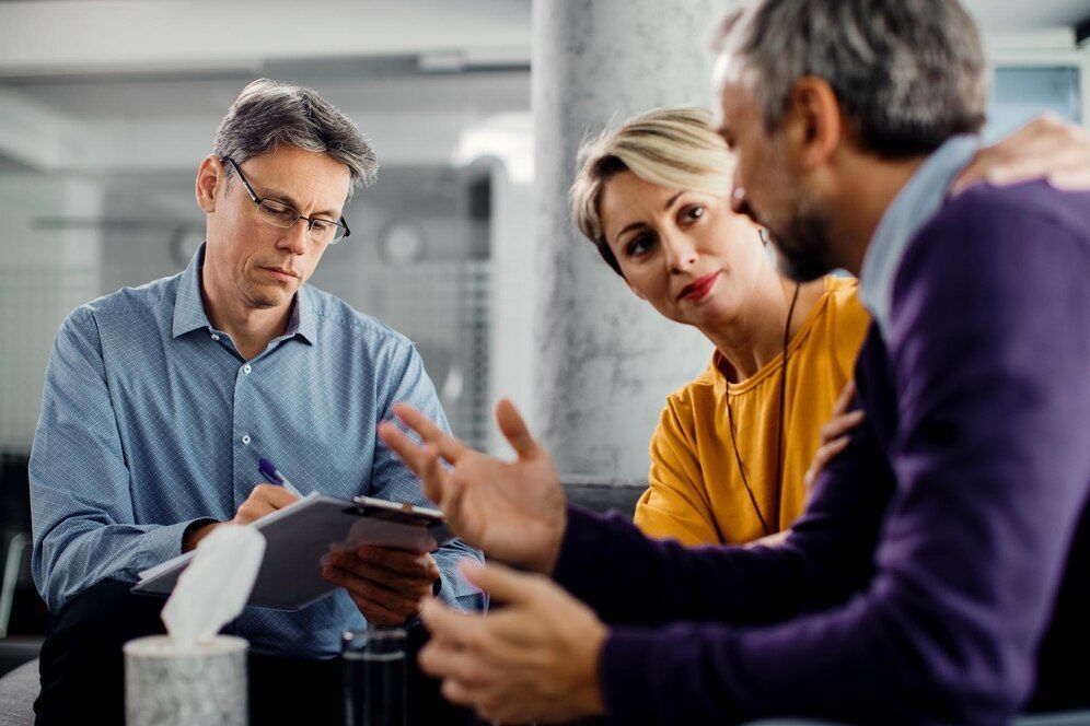 A group of people are sitting around a table talking to each other.