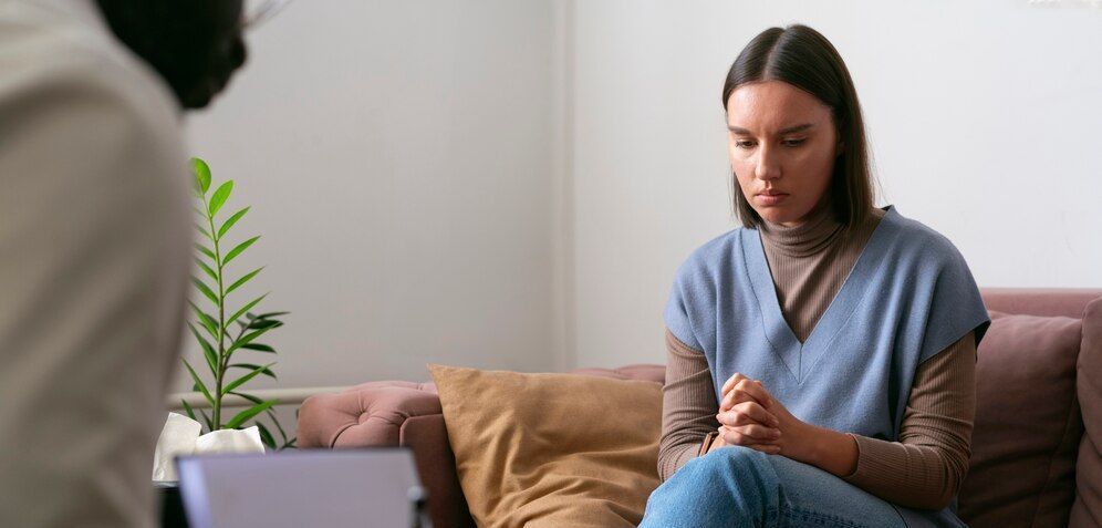 A woman is sitting on a couch talking to a counselor.