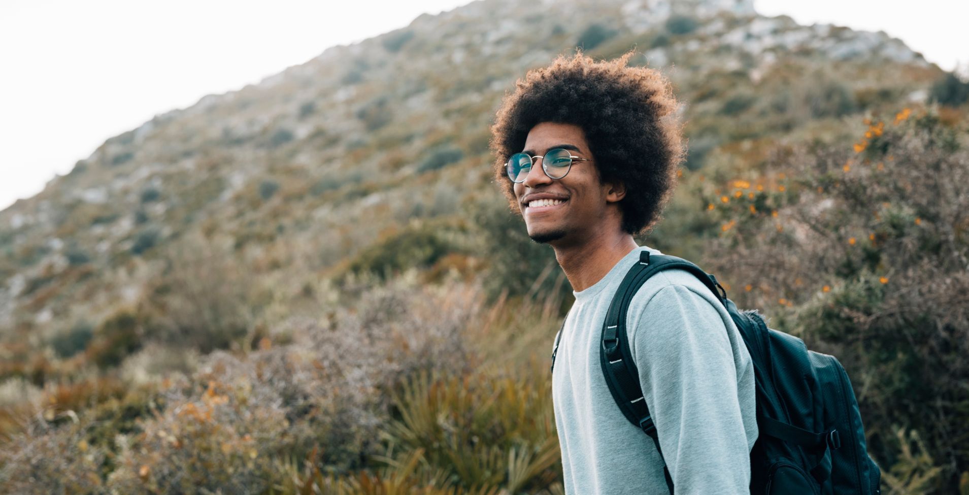 a man with a backpack is standing on top of a hill.