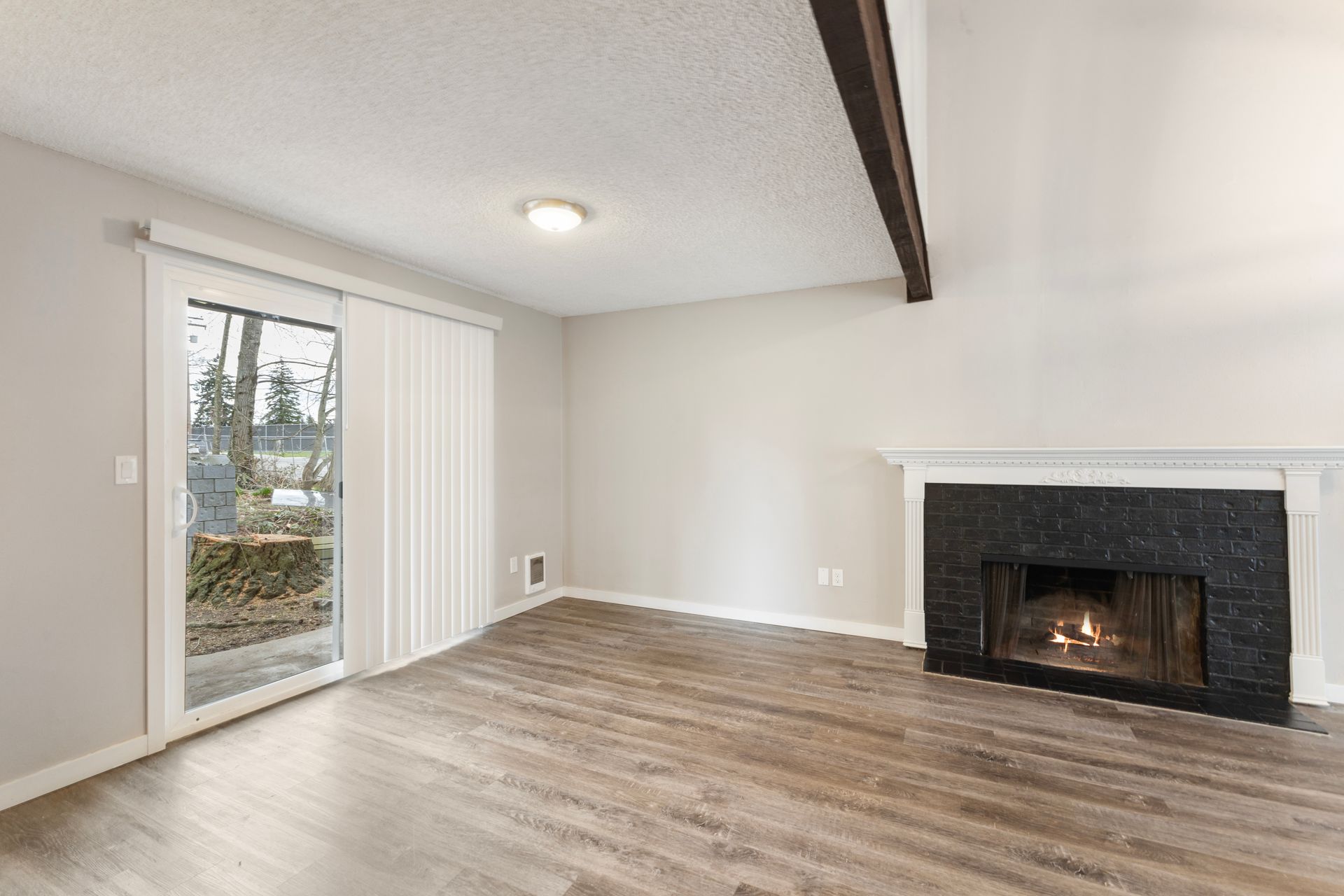 An empty living room with a fireplace and sliding glass doors.