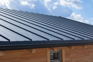 Dark metal roof on a wooden building under a blue sky with clouds