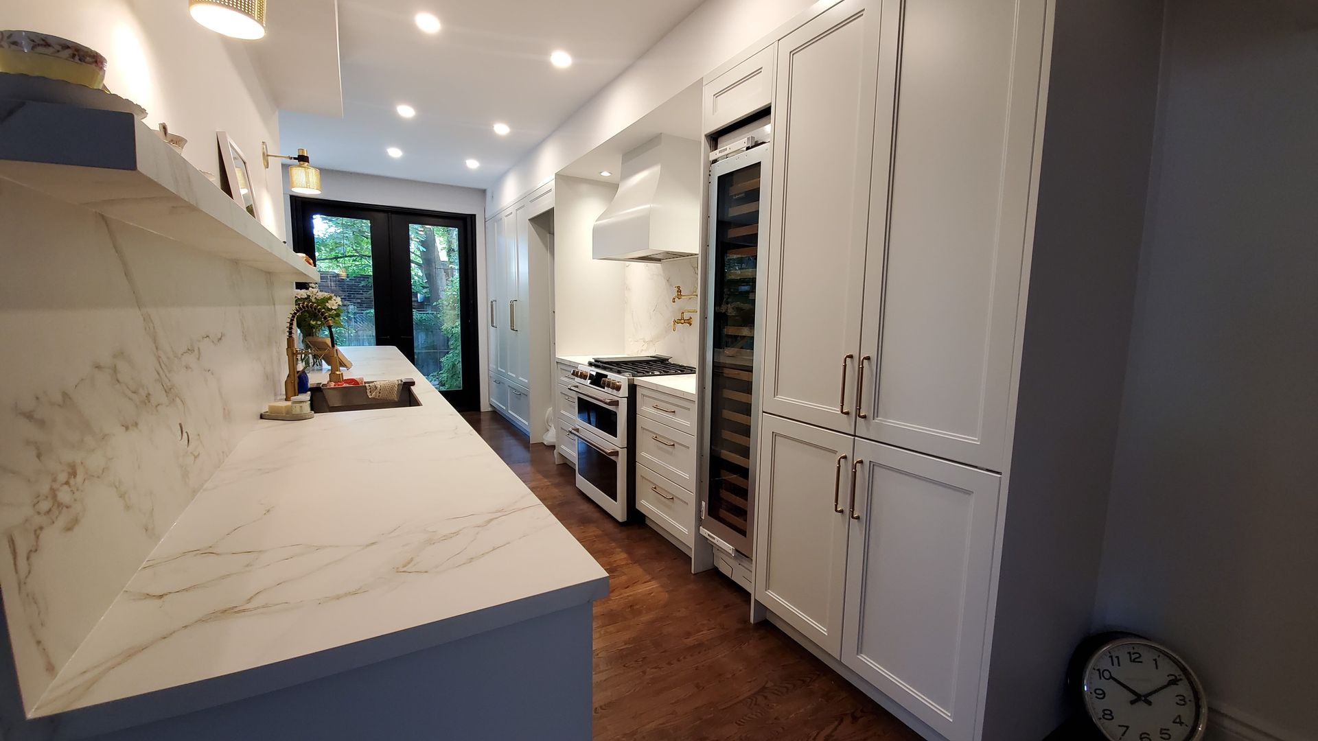 A kitchen with white cabinets and a clock on the wall.