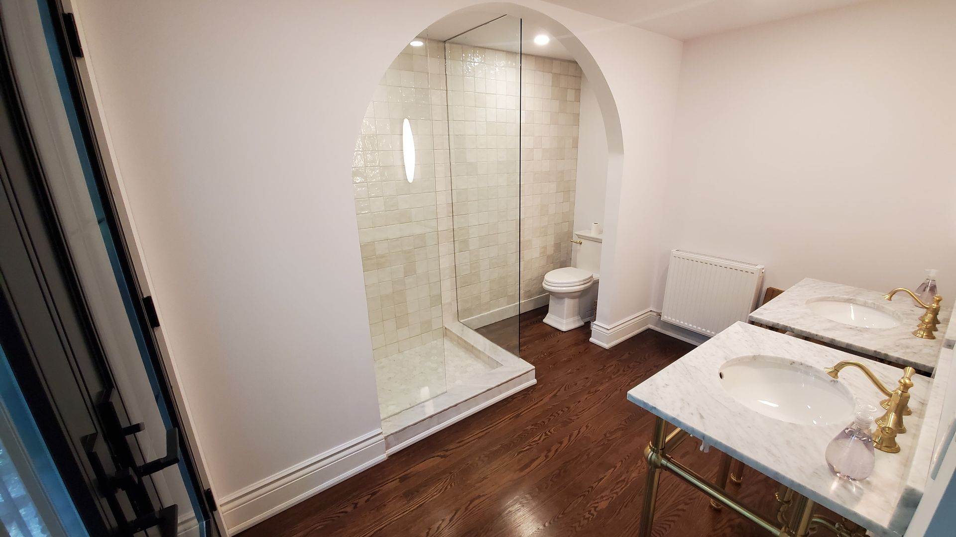A bathroom with two sinks , a toilet , and a walk in shower.