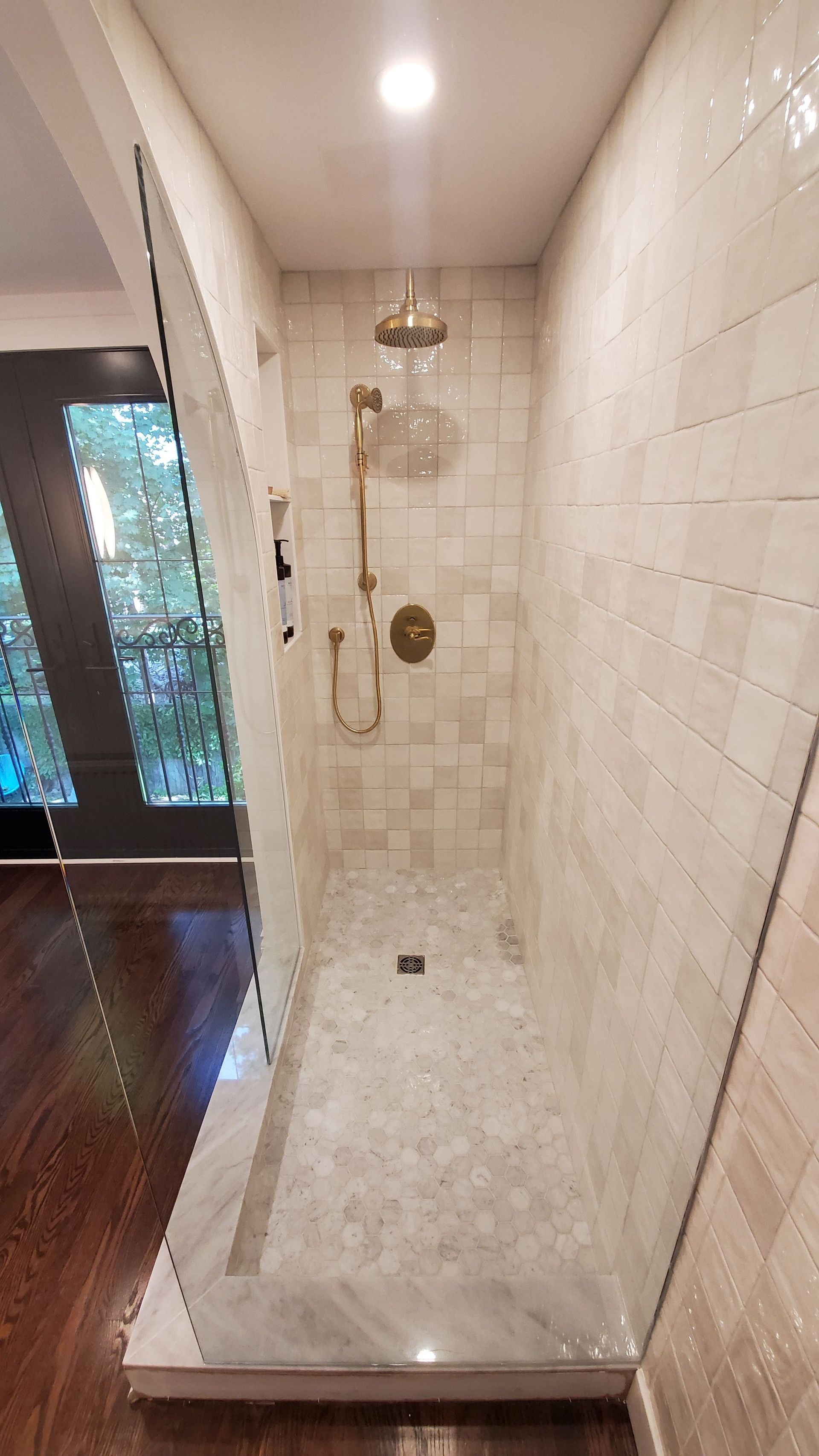 A walk in shower with a glass door and a shower head.
