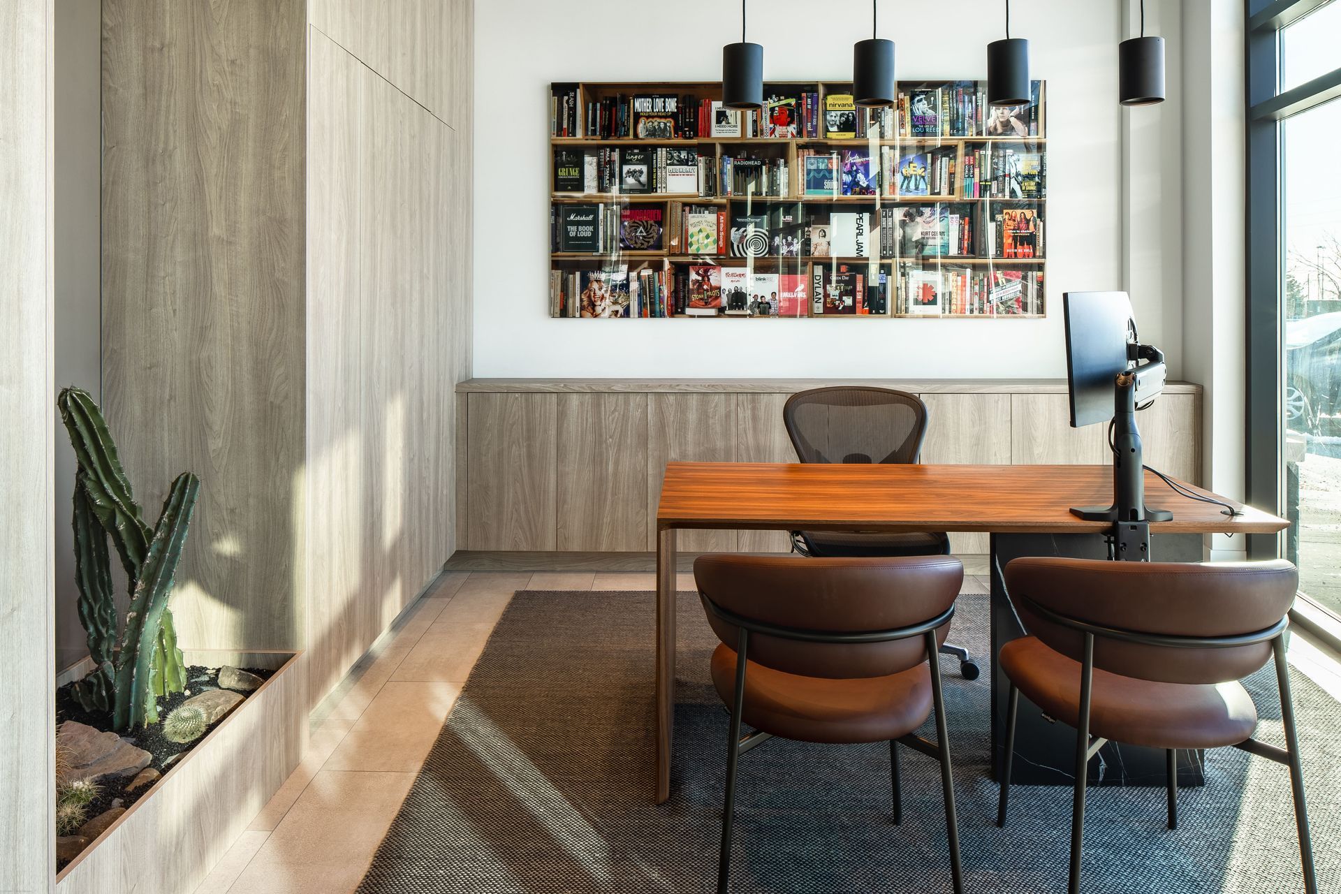 A room with a table and chairs and a bookshelf on the wall.