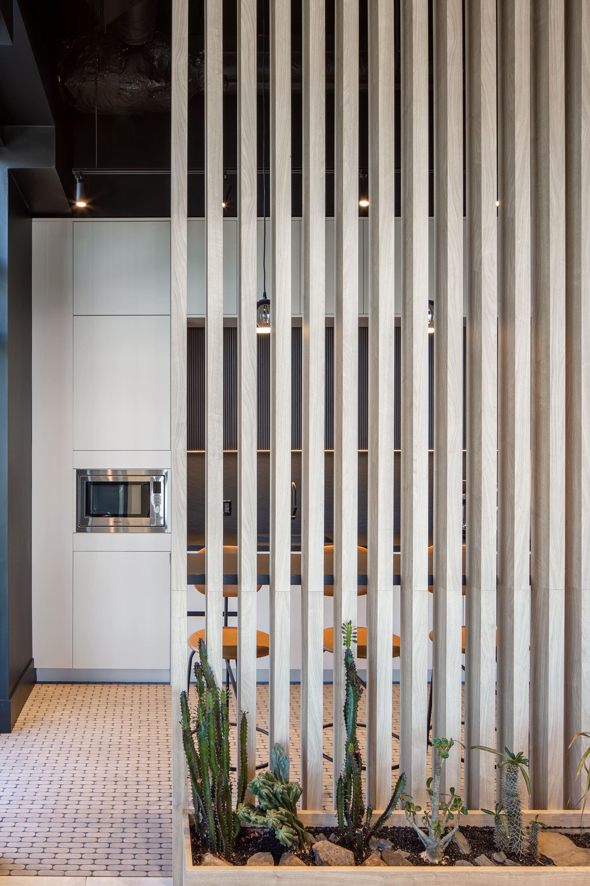 A room with a divider made of wooden slats and plants in a planter.