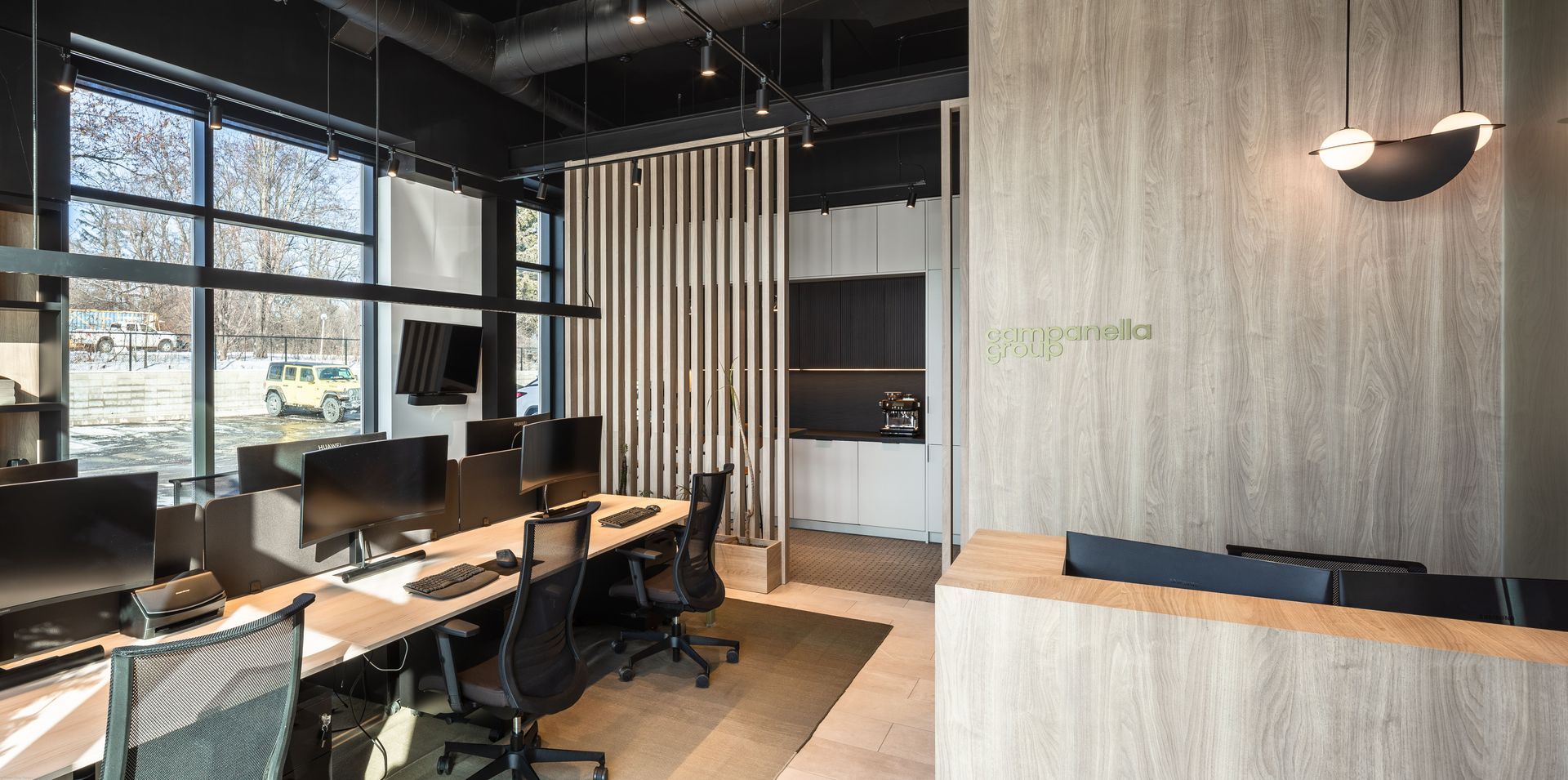 A modern office with a lot of desks and chairs and a reception area.