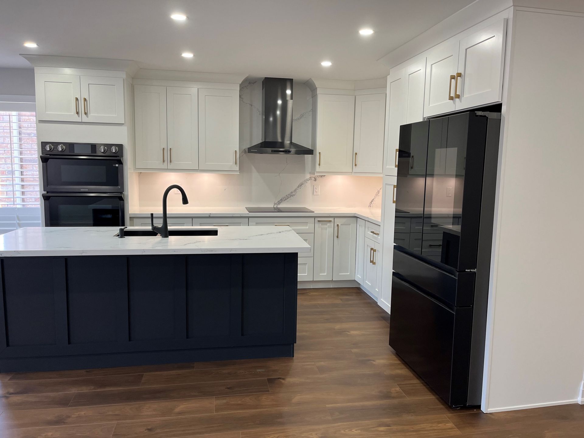 A kitchen with white cabinets and a black refrigerator.
